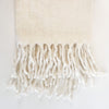 The Fireside throw is woven in a soft ivory wool blend and brushed for an airy, lofty touch. Finished with luxurious fringe edges. A luxe layer that works with any neutral decor. Measures 50" x 65".