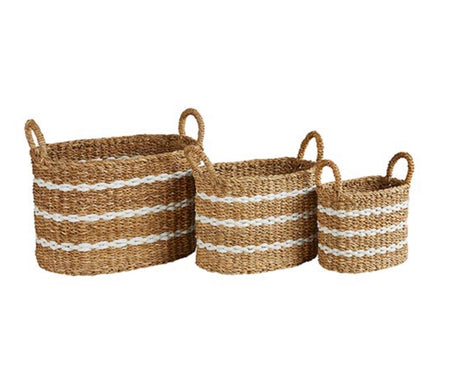Coastal stripe storage baskets shown in large, medium and small sizes. Each sold separately. Woven in natural seagrass with three white stripes. Oval shape with handles on each side.