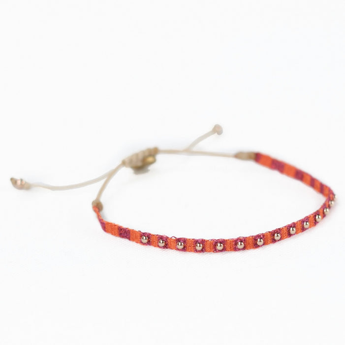 Guava 6 friendship bracelet woven in fuchsia and orange stripes and embellished with tiny brass beads. Pull string adjuster, one size fits most.