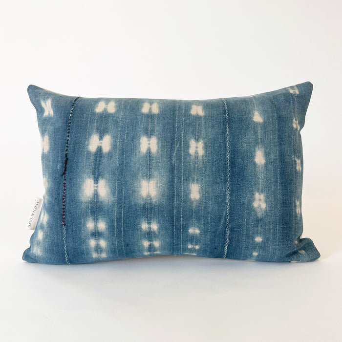 Small Zola pillow in shibori pattern 2.5. Faded indigo and natural shibori "tie dye" pattern with vertical mending stitches in eggplant and light blue. Natural Belgian linen back. Measures 19" x 13". Limited edition.