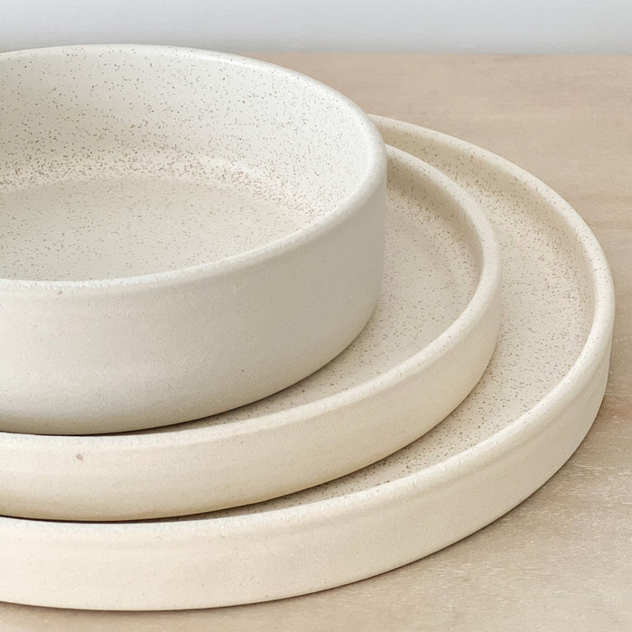 Mesa stoneware dinner collection. Small batch stoneware made in Portugal. Clean, linear silhouette finished in a creamy white glaze perfect for the modern dining table. Each piece sold separately.