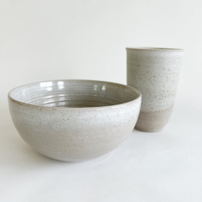 Stoneware Bayside bowl and travel mug. The soft grey glaze with sandy speckles is perfect for the  coastal or farmhouse table. Each sold separately.