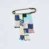 Brass Pin beaded with strings of blue, cream, pink, light blue & red glass beads. A colorful friendship pin by Alice Rise.